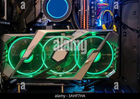 Die Hochleistungs-Grafikkarte in Nahaufnahme mit Lüfter und mehrfarbigem LED-RGB-Licht zeigt den Status beim Arbeiten, im Computergehäuse und im Heimwerker an Stockfoto