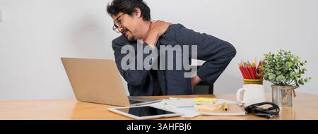 Büroangestellte, die den ganzen Tag am Schreibtisch sitzen müssen. Mann, Schulterschmerzen und Laptop während der Arbeit im Büro, leiden unter Stress, Depressionen und Verbrennungen Stockfoto
