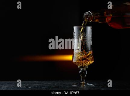 Harter Alkohol wird in ein Glas gegossen. Schwarzer Hintergrund mit Kopierraum. Stockfoto