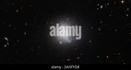 15. April 2015 - ..die Sterne im Zentrum des Hubble-Weltraumteleskops der NASA/ESA sind eine Galaxie, die als UGC 5797 bekannt ist. Hubble fängt eine Galaxie ein, die sich derzeit einer aktiven Sternentstehung unterzieht - April 2015. Die Verwischung der Sterne im Zentrum dieses Hubble-Weltraumteleskops der NASA/ESA ist eine Galaxie, die als UGC 5797 bekannt ist. UGC 5797 ist eine Emissionskalaxie, was bedeutet, dass sie derzeit einer aktiven Sternentstehung unterliegt. Das Ergebnis ist eine Sternpopulation, die ständig renoviert wird, da sich riesige hellblaue Sterne bilden. Galaxien mit fruchtbarer Sternentstehung sind nicht nur blau getönt, sondern auch ke Stockfoto