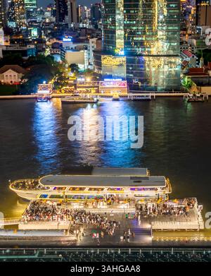 Bangkok, Thailand - 02. Juli: Nächtliche Szene des Flusslebens, beleuchtete Skyline der Stadt und Flussboote, Blick von der obersten Etage, Außenterrasse des Wahrzeichens Stockfoto