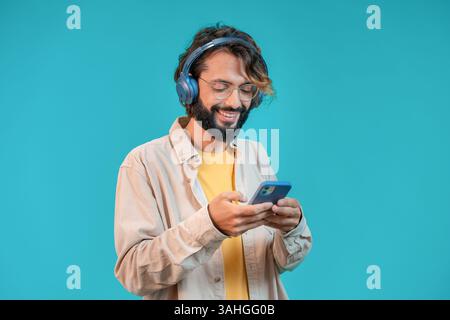 Junger Mann, der seine Lieblingsmusik genießt, während er Kopfhörer trägt und sein Smartphone benutzt Stockfoto