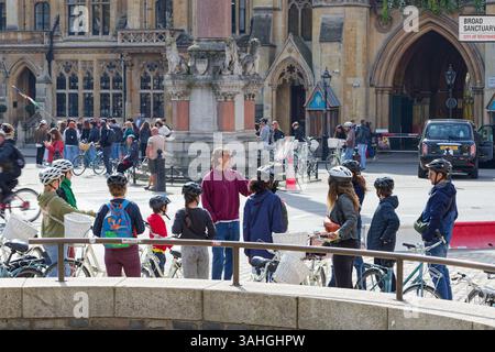 Touristen auf einer Fahrradtour durch das Zentrum von London mit ihrem Reiseleiter. Personen, die in einer Gruppe stehen und dem Reiseleiter zuhören, erzählen ihnen mehr über die Geschichte. Stockfoto