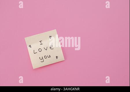 Ein rosafarbener Hintergrund mit einem Aufkleber mit den Worten „Ich liebe dich“, ideal für romantische Themen und Geschenke Stockfoto