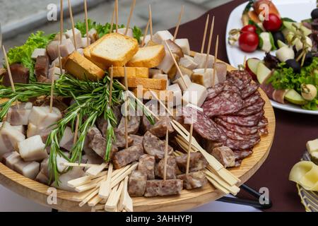 Eine große Holzplatte zeigt eine Auswahl an Wurst, Käse und Brot, garniert mit frischen Kräutern. Das Aufstrich ist Teil einer kulinarischen Veranstaltung i Stockfoto