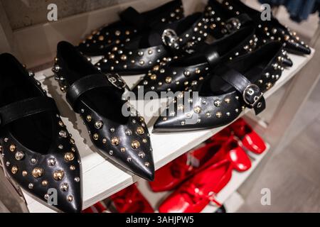 Stilvolle schwarze Lederflaches mit Nieten und roten Schuhen in einer Ladenpräsentation. Stockfoto