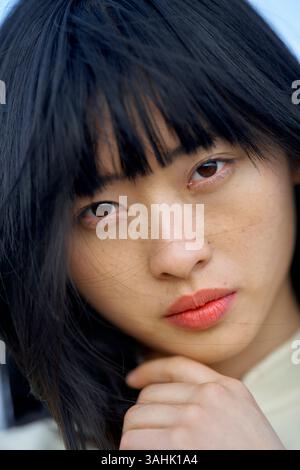Nahaufnahme einer Frau mit langen schwarzen Haaren und leuchtend rotem Lippenstift, die aufmerksam blickt. Brandenburg, Deutschland Stockfoto