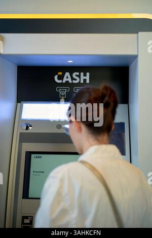 Frau, die einen Geldautomaten in einer modernen Bankumgebung benutzt. Brüssel, Belgien Stockfoto