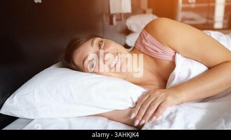 Frau, die friedlich schläft und lächelnd im Hotelzimmer aufwacht Stockfoto