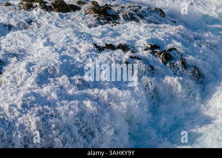 Meereswellen krachen kraftvoll gegen felsiges Ufer und erzeugen weißen Schaum und dynamische Bewegungen. Monterey, CA, USA Stockfoto