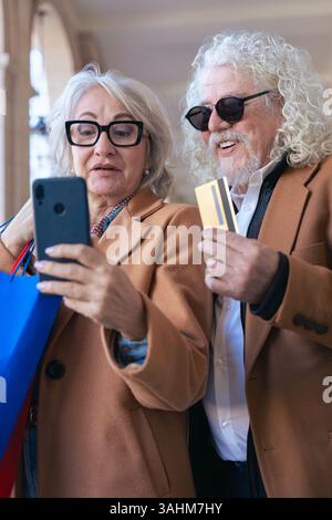 Kaukasisches Seniorenpaar, das im Freien mit Smartphone und Kreditkarte einkaufen kann Stockfoto