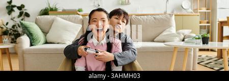 Ein junges asiatisches Paar genießt ihre Zeit zu Hause, lacht und spielt gemeinsam Videospiele, Banner Stockfoto