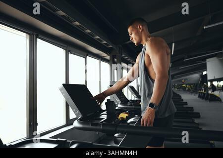 Sportlich attraktiver junger fokussierter Mann, der auf Laufbahn läuft, auf Gesundheit und Fitness arbeitet. Stockfoto