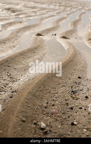Dies ist eine detaillierte Nahaufnahme eines wunderschönen Sandstrandes mit sanften Wellen, die gegen das Ufer plätschern und eine ruhige Küstenszene schaffen Stockfoto