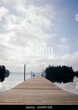 Eine friedliche Szene eines hölzernen Bootsanlegeplatzes auf einem See in Schweden, umgeben von ruhiger Natur. Stockfoto