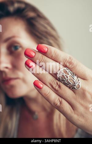 Schöne Frau mittleren Alters zeigt rote Schellack Maniküre auf Nägeln. Stockfoto