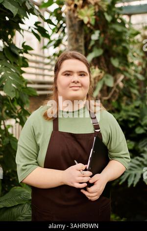 Eine junge Frau mit Down-Syndrom zeigt ihr Selbstvertrauen in üppigem Grün. Stockfoto