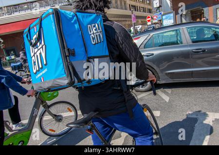 Delicity Food Delivery Fahrradfahrer in einer Straße von Paris. Delicity ist eine französische Fair-Trade-Plattform für die Bestellung, Lieferung und Buchung von Restaurants Stockfoto