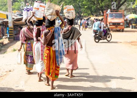 Lokaler Wochenmarkt eines Stammes der Dongria Kondh in Orissa in Indien, Frauen in farbenfroher traditioneller Kleidung mit Körben auf dem Kopf Stockfoto