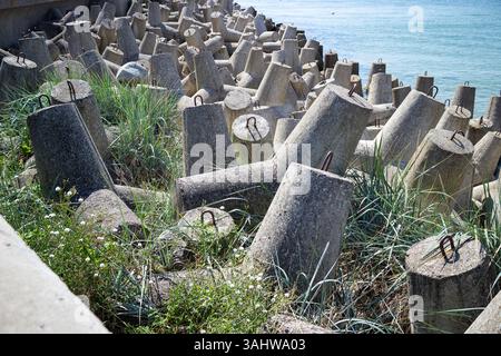 Ein Haufen Betonblöcke und ein paar andere Objekte sind um ein Gewässer verstreut. Die Szene ist etwas chaotisch und desorganisiert, mit dem Objec Stockfoto