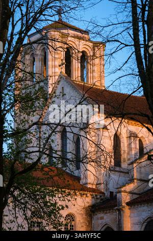 Detaillierte vertikale Ansicht der äußeren Westseite der Kirche bei Sonnenaufgang, mit Bäumen, die umrahmt werden und blauem Himmel Stockfoto