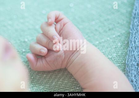 „Nahaufnahme einer Hand eines Neugeborenen, die sanft den Finger eines Elternteils hält – weiches natürliches Licht, intimer Familienmoment“ Stockfoto
