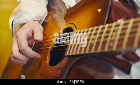 Nahaufnahme der Akustikgitarre, die gespielt wird. Eine detaillierte Nahaufnahme einer Person, die die Saiten einer Akustikgitarre umspielt. Stockfoto