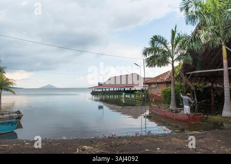 Fischer arrangieren seine Fischernetze an der überfluteten Küste von Puerto Momotombo. Momotombito Island im Hintergrund. Lake Managua, Nicaragua Stockfoto