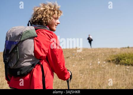 Ein junger, glücklicher männlicher Reisender liebt Teamwandern oder Trekking Trail Mountain, aktiven Lebensstil und Abenteuerreisen. Stockfoto