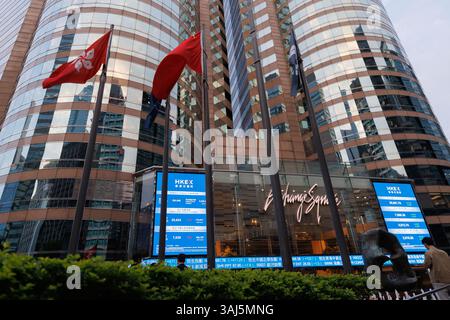 Eine Hongkong- und China-Flagge neben der elektronischen Platine, die den Preis des Hang Seng Index am Börsenplatz anzeigt. Die asiatischen Märkte stiegen am 10. April 2025 an, wobei der Hang Seng Index solide Gewinne verzeichnete, nachdem Donald Trump eine 90-tägige Pause bei Zöllen gegen US-Verbündete angekündigt hatte. Diese Entwicklung ging mit einer drastischen Erhöhung der Zölle auf chinesische Waren einher, die sich um bis zu 125 % erhöhten. Stockfoto