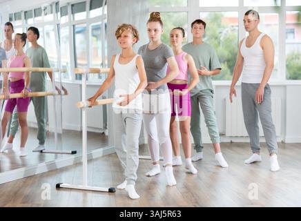 Der Lehrer führt Unterricht mit Mädchen und Jungen im Ballettstudio und beobachtet Batman-Übungen. Stockfoto