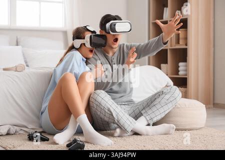Verängstigte junge Paare mit VR-Brille im Schlafzimmer Stockfoto