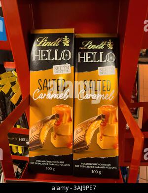 Zwei lindt Hello Salt Karamell Schokoladentafeln stehen auf einem roten Regal, bereit zum Kauf - FRANKFURT, DEUTSCHLAND - 9. APRIL 2025 Stockfoto