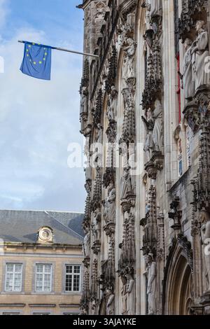 Die Europäische Flagge, die über den ornamentalen Statuen auf der gotischen Fassade des Brügger Rathauses (Stadhuis) auf dem Burgplatz in Brügge schwingt. Stockfoto