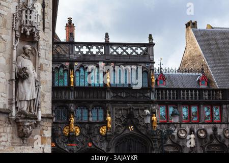 Detail der gotischen Fassade des Brügge Rathauses (Stadhuis) auf dem Burgplatz, mit der Basilika des Heiligen Blutes im Hintergrund. Stockfoto