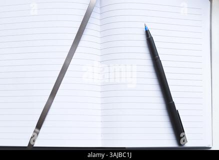 Ein schwarzer Stift auf einem offenen Notizbuch mit linierten Seiten und einem Platzhalter für ein graues Band Stockfoto