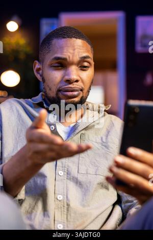 Black Guy besucht einen virtuellen Workshop-Vortrag über eine Online-Konferenz und nimmt an der Diskussion in seinem Haus Teil. Junge Person, die an einer Videokonferenz teilnimmt, interaktives Lernen. Stockfoto