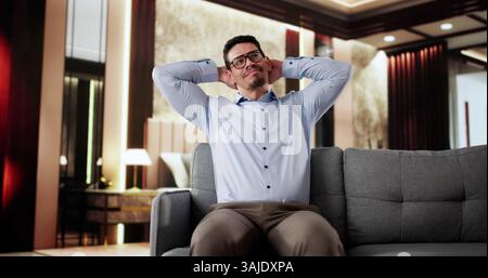 Glücklicher Mann, Der Auf Sofa Sitzt Und Im Hotel Denkt Stockfoto