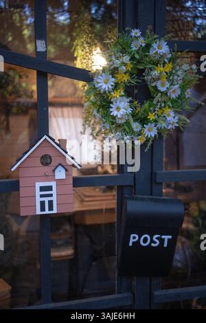 Ein kleines Holzhaus mit Blumen und einem Schild für die Post. Stockfoto