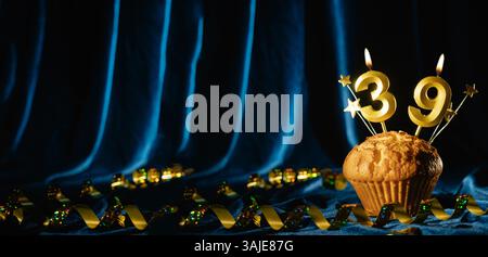Nummer 39 goldene Festkerze und kleine Sterne in süßem Cupcake auf hellblauem Samthintergrund. Konzept der Feier von Geburtstag, Jubiläum Stockfoto