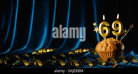 Nummer 69 goldene Festkerze und kleine Sterne in süßem Cupcake auf hellblauem Samthintergrund. Konzept der Feier von Geburtstag, Jubiläum Stockfoto