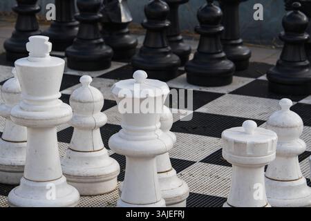 Majestätische riesige Schachfiguren, die direkt auf der Straße installiert sind, laden Passanten zu einer faszinierenden Schlacht der Vernunft ein. Stockfoto