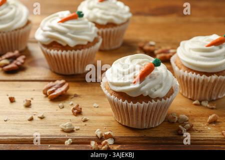 Leckere Karotten-Cupcakes und Walnüsse auf Holztisch, Nahaufnahme Stockfoto