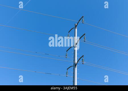 Elektrischer Pol gegen einen klaren blauen Himmel Stockfoto