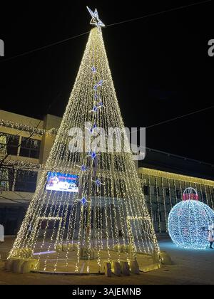 Hell erleuchteter Weihnachtsbaum und Ornamente, die während einer festlichen Feiertagsnächteszene in Madrid, Spanien, festgehalten wurden. Stockfoto