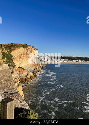 Blick auf das Meer in der Nähe von Nazare, Portugal, mit dramatischen Klippen, Wellen und sonnigem Wetter. Stockfoto