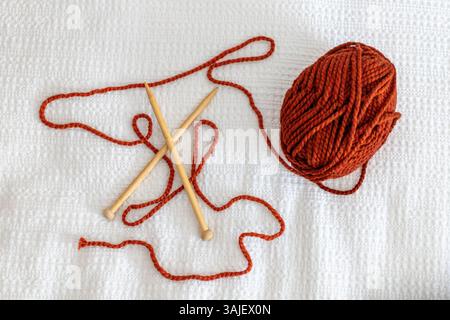 Verbranntes orangefarbenes Garn und Stricknadeln Stockfoto