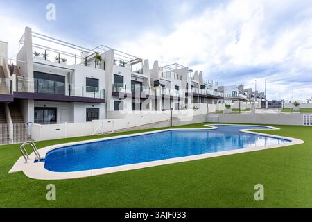 Hellblauer Gemeinschaftspool in einem Landschaftsbereich mit modernen Apartments dahinter. Stockfoto