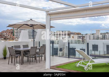 Moderner Essbereich im Freien mit Sonnenschirm und Stadtblick. Stockfoto