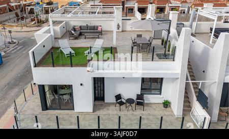 Blick auf die Dachterrasse mit Sonnenliegen, Sitzgelegenheiten im Freien und Essbereich. Stockfoto